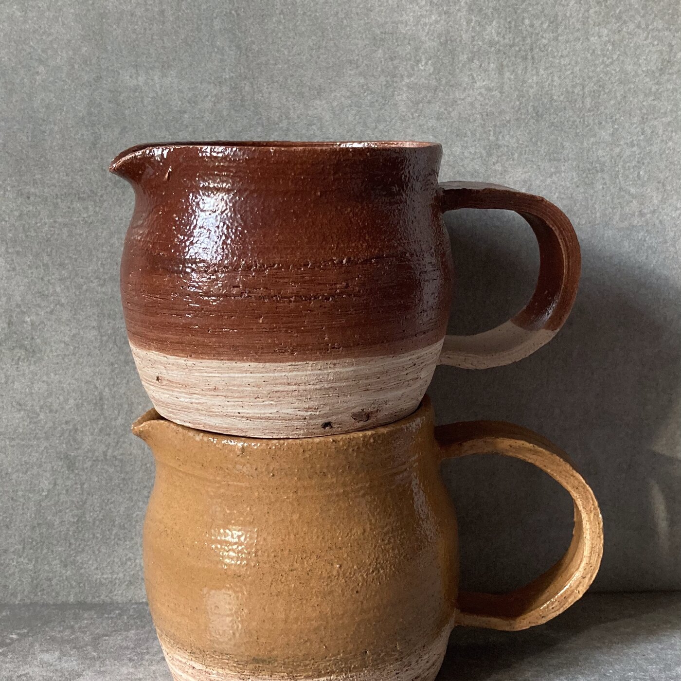 Stacked handmade stoneware creamers in rust and sand glazes