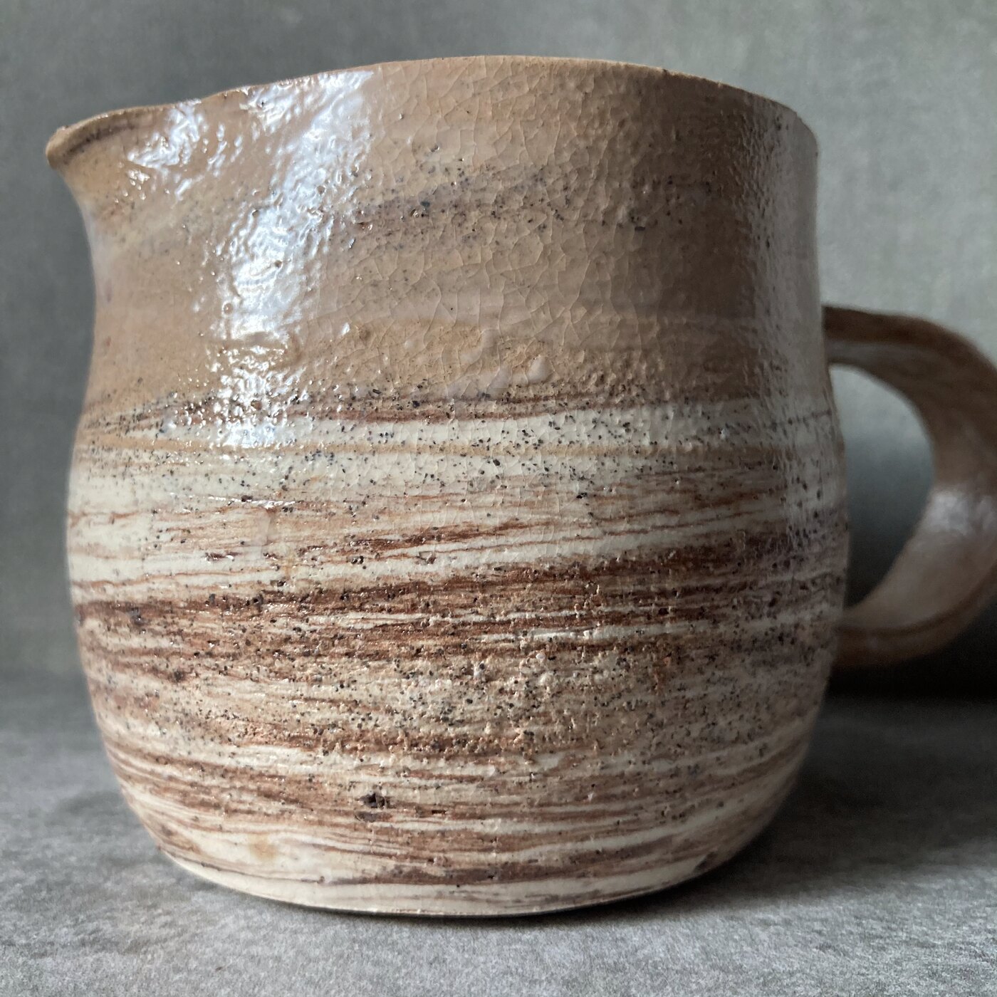 A large handmade stoneware pitcher with banded glaze